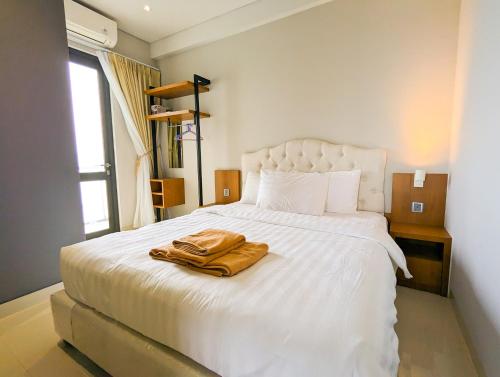 a bedroom with a white bed with a robe on it at Lovina 21-AA at One Residence in Batam Center