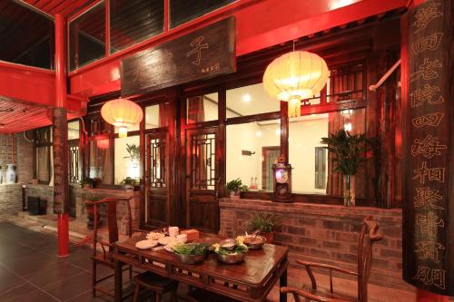 a restaurant with a wooden table and chairs and lights at The Great Wall Courtyard Hostel in Yanqing