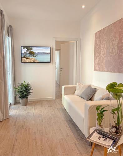 a living room with a white couch and a painting on the wall at La Maison Fois - Appartamento Quartucciu in Quartucciu