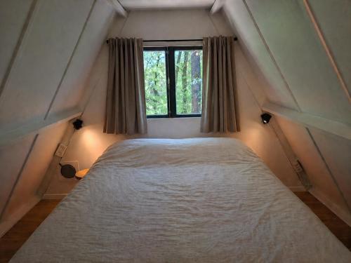 a bedroom with a bed with a window at Woodpecker - bungalow 29 in Durbuy
