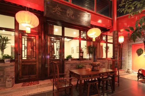 a restaurant with a wooden table and chairs and lights at The Great Wall Courtyard Hostel in Yanqing