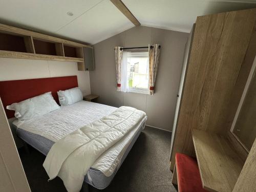 a small bedroom with a bed and a window at Royal Oak Caravan Park in Skegness