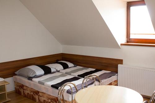 a bed in a room with two chairs and a table at Penzion Leona in Obecnice