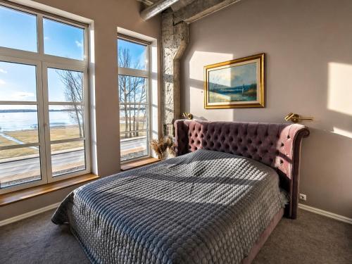 a bedroom with a large bed and windows at Tamula Lake View Apartment in Võru