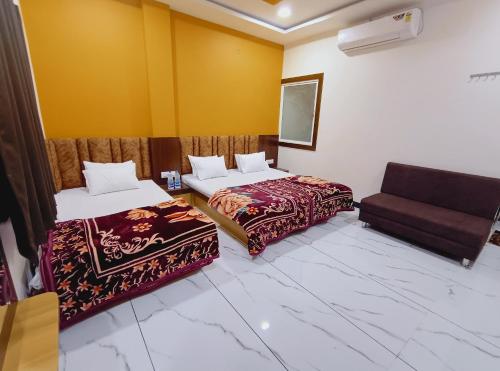 a hotel room with two beds and a couch at Hotel Shree Raghunandan Palace in Ujjain