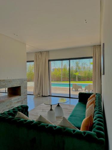 a living room with a green couch and a fireplace at Villa Dream el filali in Sraghna