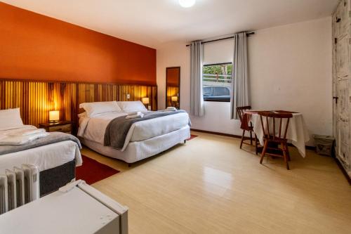 una habitación de hotel con dos camas, una mesa y un escritorio en Hotel Ascona, en Campos do Jordão