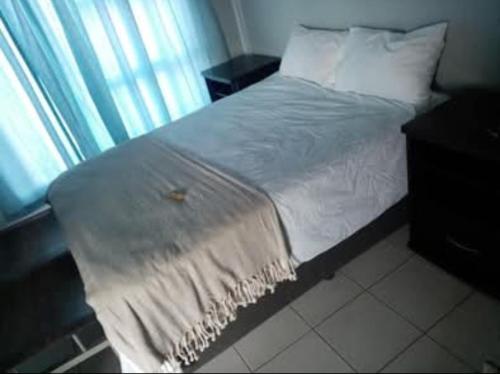 a bed with white sheets and pillows next to a window at The Seige Guesthouse in Pretoria