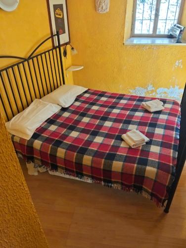 a bed with a plaid blanket and two towels on it at Appartamento Gelsomino in Montale