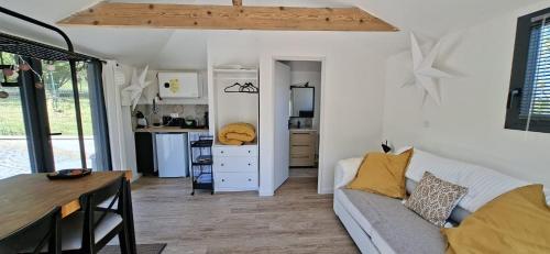 a living room with a couch and a kitchen at Cabane Cozy & Calme in Janville