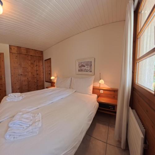 a bedroom with a white bed and a window at Wellness apartment with pool and terrace in Lenzerheide