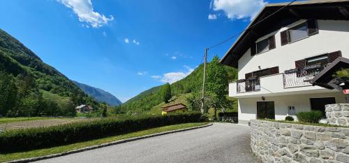 a house on a road with mountains in the background at Apartma Šmarnica in Slap ob Idrijci
