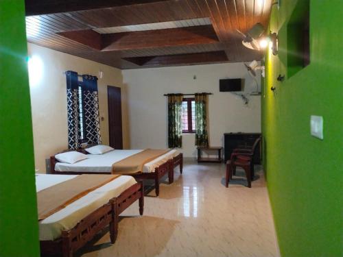 a bedroom with two beds and a television in it at Adhivilla resort in Thirunelli
