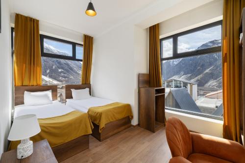 ein Hotelzimmer mit zwei Betten und einem großen Fenster in der Unterkunft Melodia KAZBEGI in Kazbegi