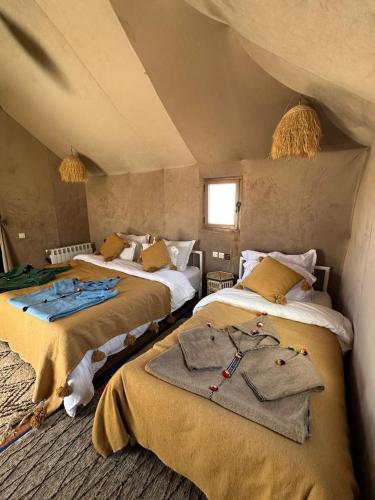 a bedroom with two beds with clothes on them at Camp Merzouga Sand Explorer in Merzouga