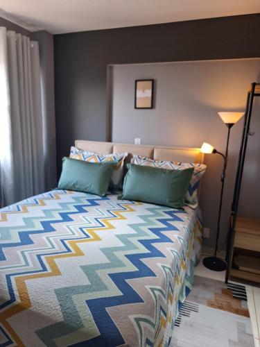 a bedroom with a bed with a colorful bedspread at Studio Elegante - Completo - AC - Garagem in Rondonópolis
