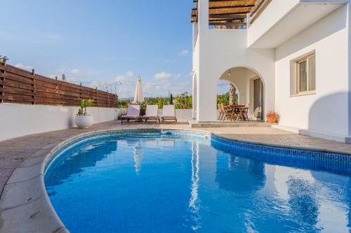a swimming pool in front of a house at Nireas Villa in Paphos