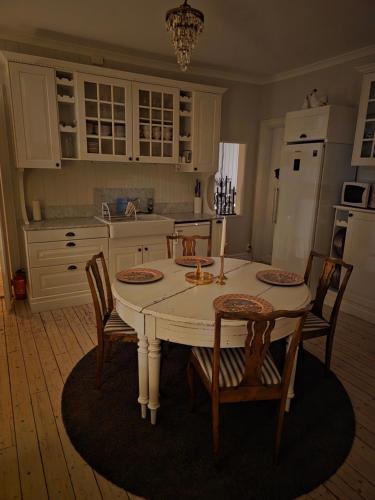 a kitchen with a white table with chairs and a white refrigerator at Nordgrenska in Åmål