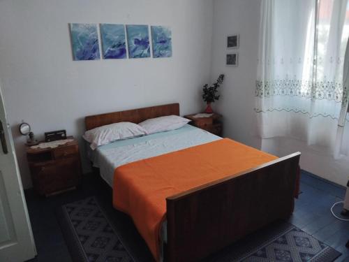 a bedroom with a bed with an orange blanket on it at Beko i Dada in Olib
