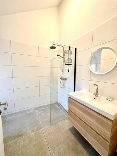 a bathroom with a sink and a shower with a mirror at Ferienhaus Fam. Mersmann in Papenburg