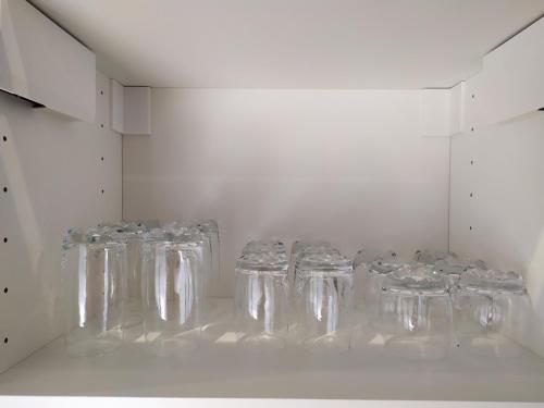 a row of clear glasses in a white cabinet at Calme et Volupté in Maxilly-sur-Saône