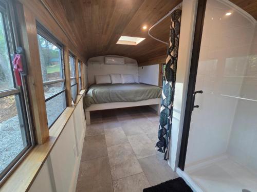 a small room with a bed in a tiny house at Lazy T Cabins - The Skoolie in Robbinsville