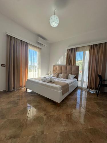 a bedroom with a large bed in a room with windows at Seli's White Villa in Ksamil