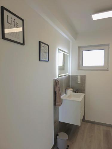a white bathroom with a sink and a mirror at Panorama trifft Gemütlichkeit FeWo Panoramablick in Nümbrecht