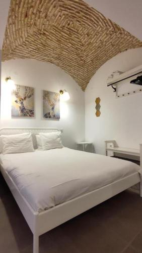 a bedroom with a white bed with a wicker ceiling at El Patinillo ENCANTO in Cáceres