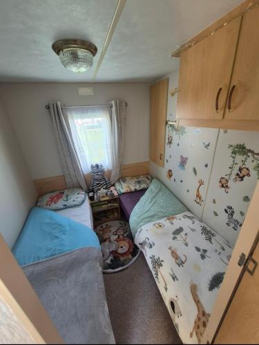 a small room with two bunk beds and a window at Jams Caravan in Skegness