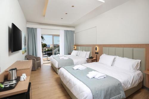 a hotel room with two beds and a television at Flegra Palace in Pefkochori