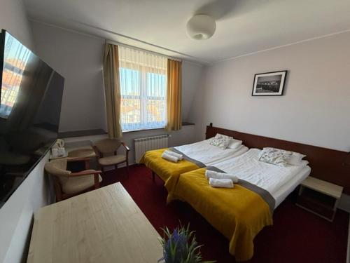 a hotel room with a large bed with yellow blanket at Hotel Aleksander in Ustka