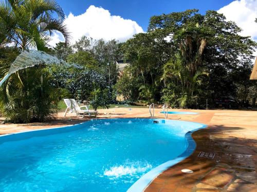 a swimming pool with blue water and palm trees at Cabañas La Carolina - Mesa de Los Santos in Los Santos