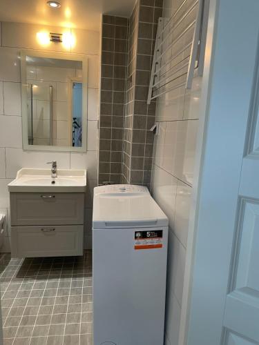 a small bathroom with a sink and a refrigerator at Fully equipped guest apartment with parking in Upplands-Väsby
