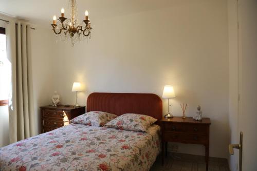 a bedroom with a bed with two night stands and a chandelier at Maison TORTONI in Bastia