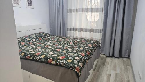 a bed with a flowered blanket on it in a bedroom at Modern Family Apartment, Free Parking, Balcony, Sleeps 5 in Bucharest