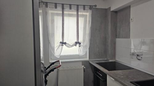 a kitchen with a window with curtains and a sink at Modern Family Apartment, Free Parking, Balcony, Sleeps 5 in Bucharest