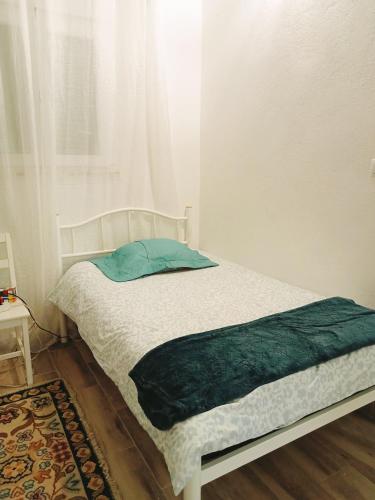 a bed with a green blanket on it in a room at Estúdio ensolarado in Fernao Ferro