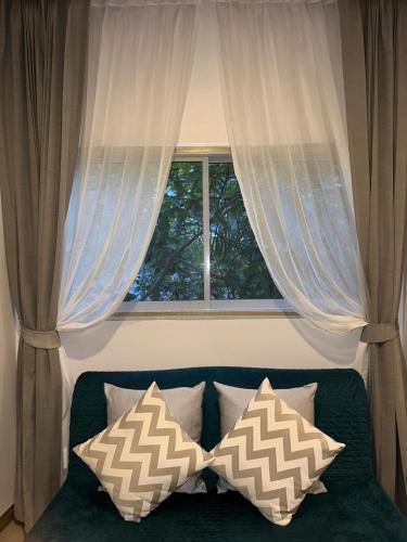 a window with curtains and pillows on a couch at Blue Sky Condo by Palmetto Karon in Ka Rorn