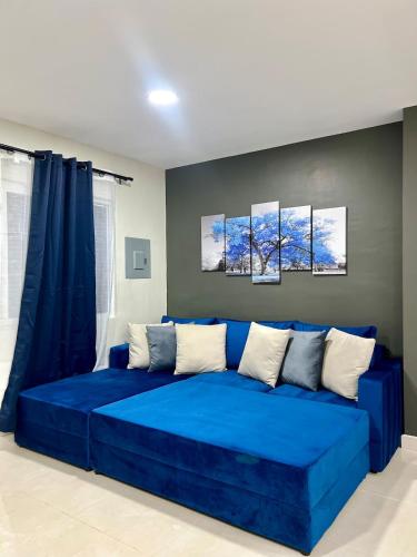 a blue couch in a room with three paintings on the wall at Rest and Reset in Usulután