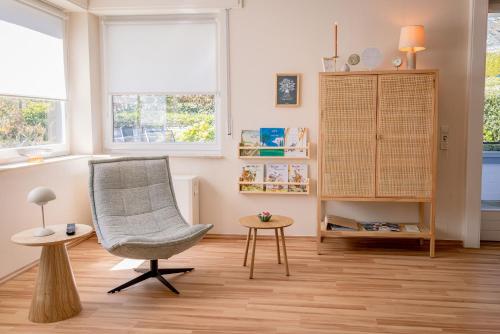 a living room with a chair and a table and windows at Wald & Weg in Schmallenberg