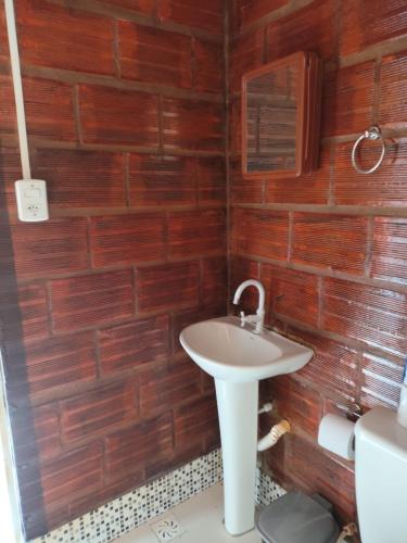 a bathroom with a sink and a wooden wall at Kitnet Rústica! in Januária