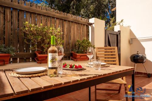 a wooden table with a bottle of wine and glasses at El Velero Piscina top y tranquilidad a 450m playa in San José