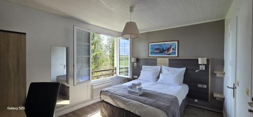a bedroom with a bed and a large window at Logis Auberges des Aulnettes in Houlgate
