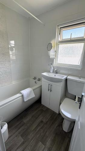 a white bathroom with a sink and a tub and a toilet at B by the sea in Scratby