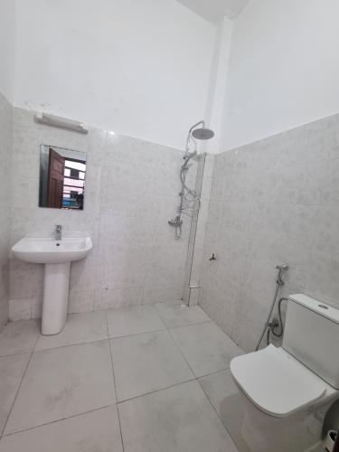 a white bathroom with a toilet and a sink at Maison Sakeena in Saint-Louis