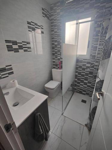 a white bathroom with a toilet and a sink at Vinaros Modern Apartment in Vinarós