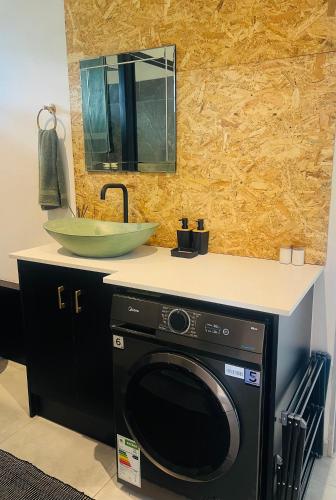 a washing machine in a bathroom with a sink at Origin Cottage in eMalahleni