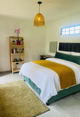 a bedroom with a large bed with a yellow and white blanket at Origin Cottage in eMalahleni