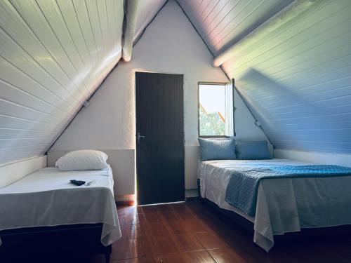 two beds in a small room with a window at Pousada Maria elza in Eldorado